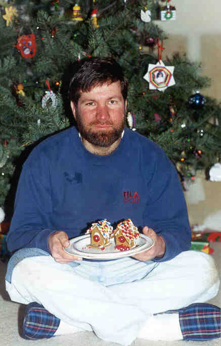 Big Dave holding a gingerbread house at Christmas